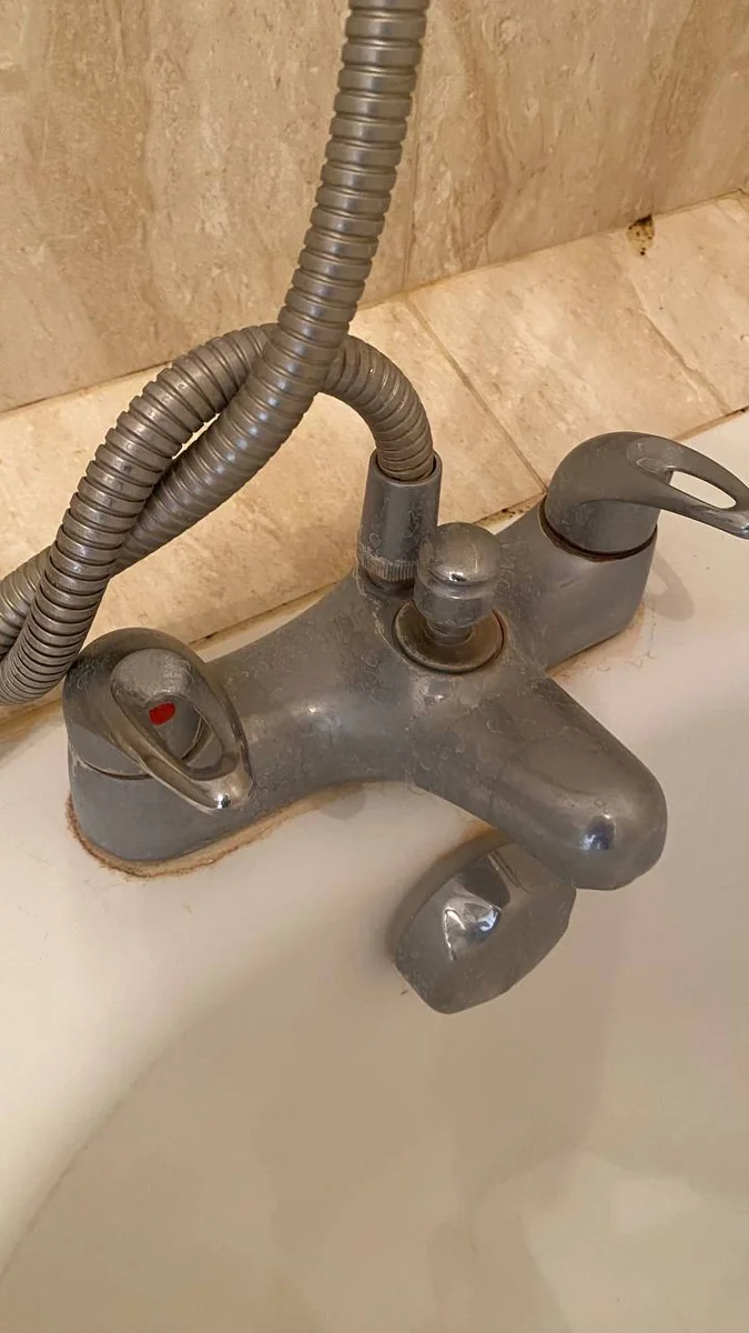 Dull bath mixer tap covered in limescale before descaling