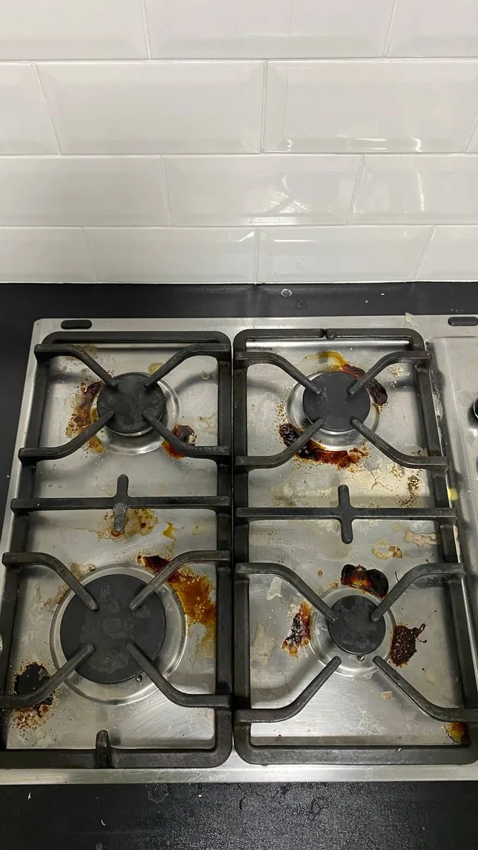 Gas hob with burnt-on food and grease before kitchen cleaning