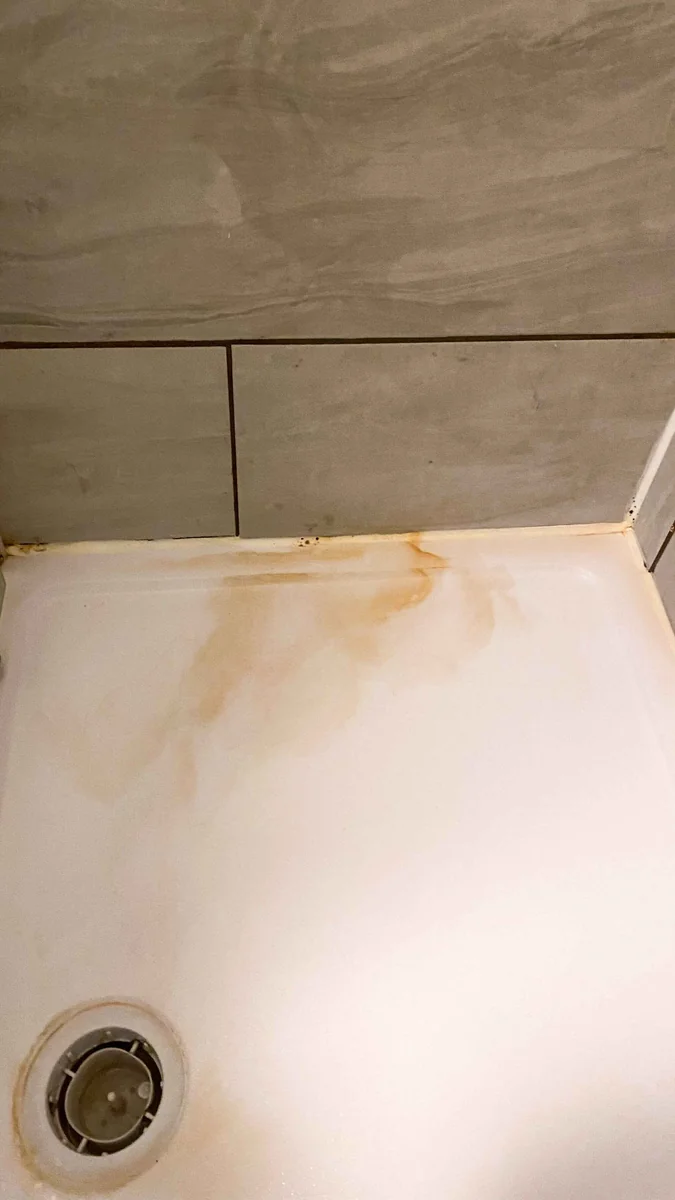 Shower tray with stains and limescale before a deep clean
